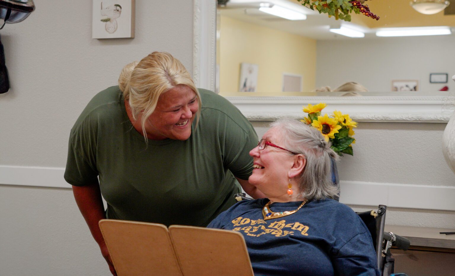 A woman smiles at a nurse at a skilled nursing care facility
