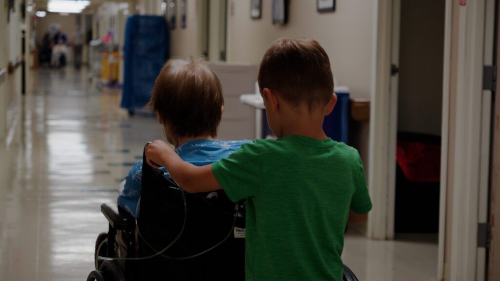 A little boy pushes his grandma in a wheelchair at a skilled nursing facility