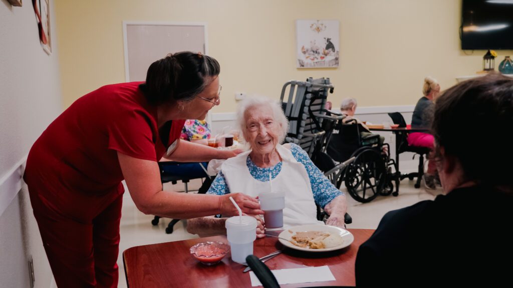 A nurse assists a long term care resident at a dining room